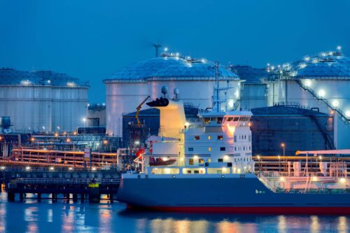 liquid natural gas storage tanks with tanker ship in foreground