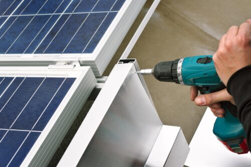 man drilling solar panels for installation
