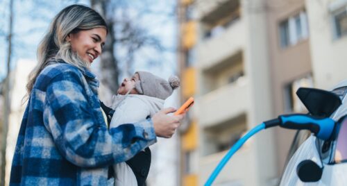 Mom charging EV with baby