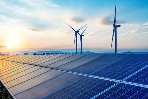 solar panels and wind turbines at sunset